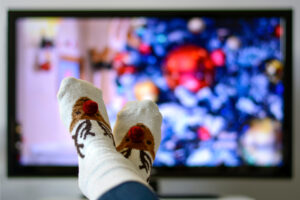 Tv con film di Natale e piedi con calze natalizie in primo piano
