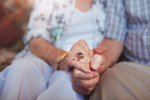Coppia anziana si tiene per mano: esmepio di amore che vince su covid