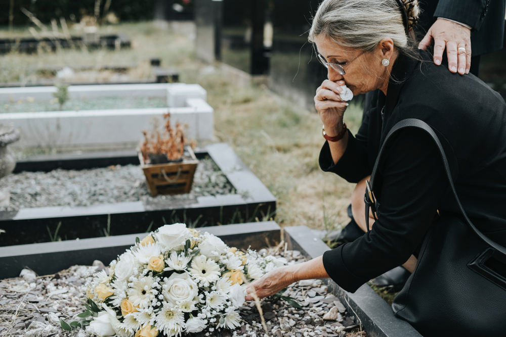 Donna presso una tomba: esempio di lutto al tempo del covid