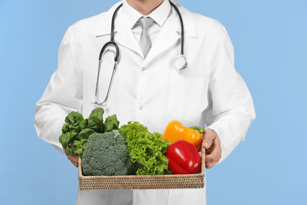 Dottore mostra verdura: esempio di consigli di alimentazione per il covid