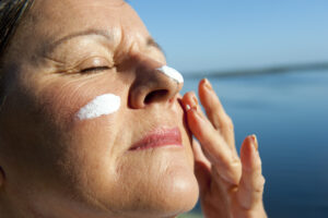 Donna prende sole con crema protettiva: esempio di effetti del sole su donne in post-menopausa